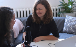 A photo of a young journalist in front of podcast equipment.