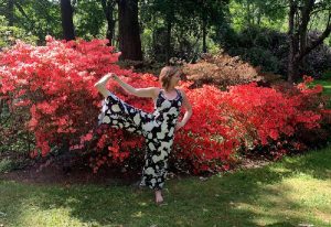 Yoga teacher Emma stretches in front a flowery bush
