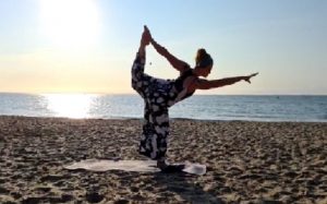 Yoga teacher Emma poses on a sunny beach