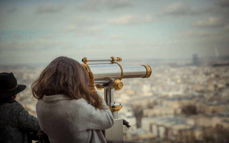 Stock image of woman looking through telescope, symbolising looking ahead at journalism predictions for 2022.