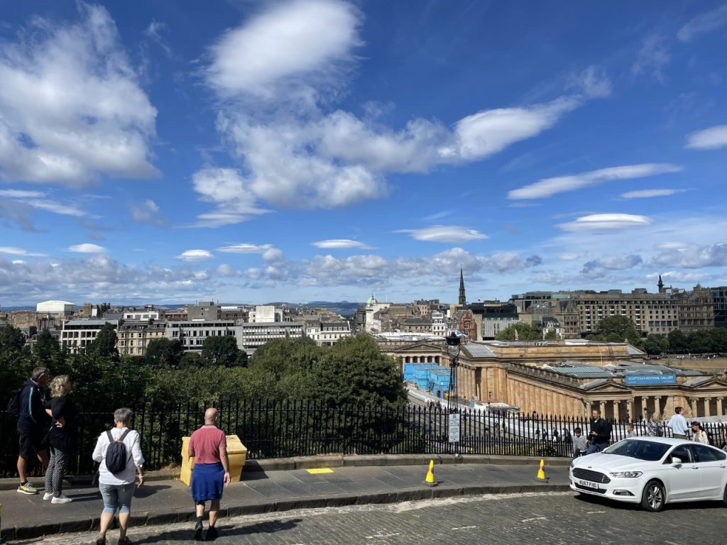 A photo of the Edinburgh skyline. There is a blue sky and some clouds. 