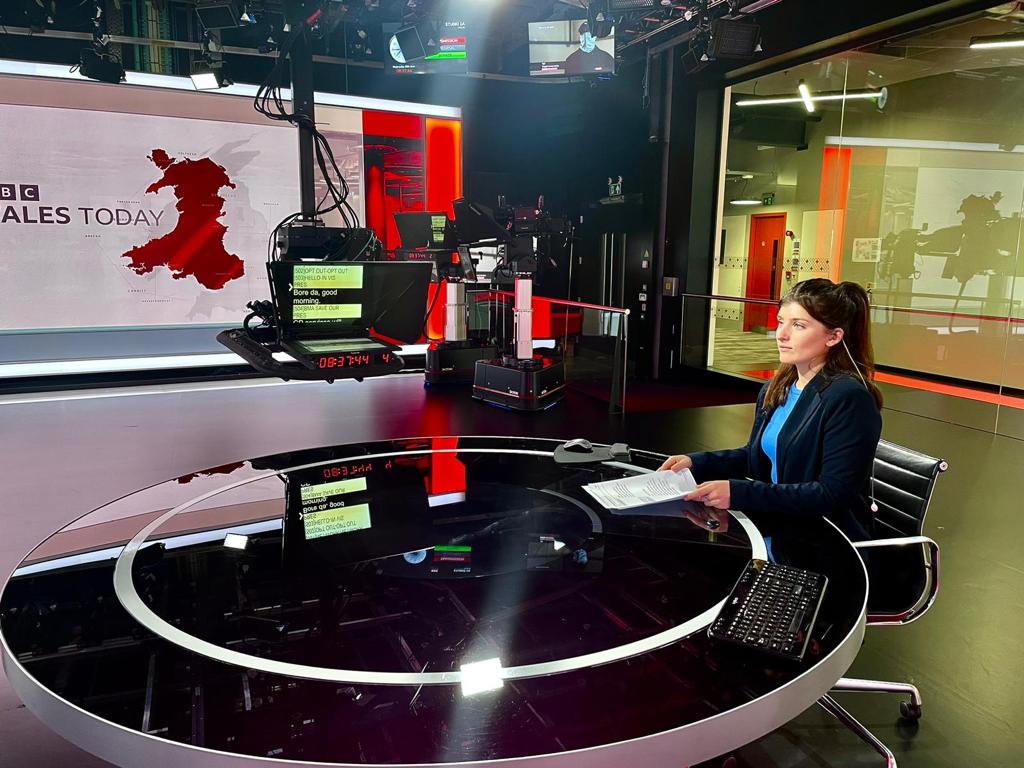A photo of Cymbeline Young pretending to present the news in a BBC studios.