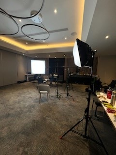 A dimly lit broadcast studio with a desk, microphones and chairs.