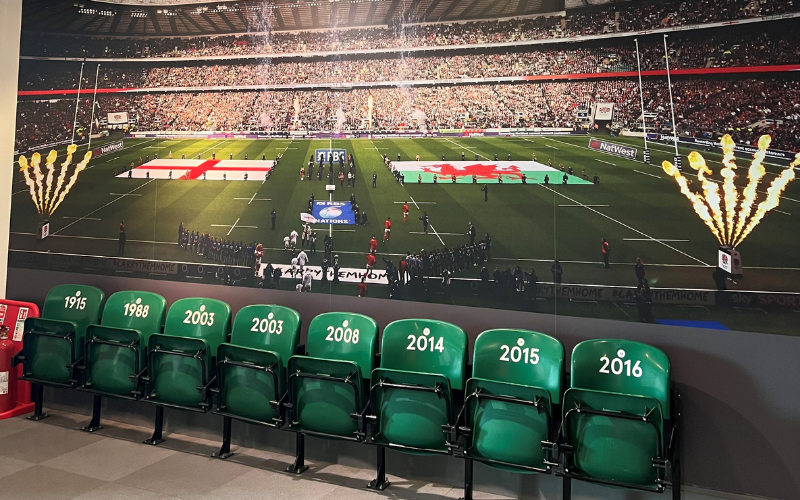 A photograph of Twickenham stadium with a photo of an England Rugby vs Wales game.