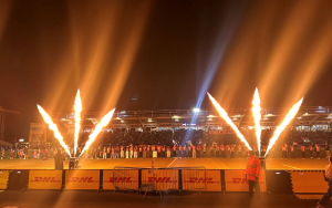 A view of the The Stoop from the stands. The players are lined up on the pitch. Fire show in front of the stand.