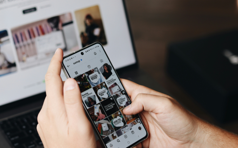 A photo of someone uploading on Instagram in front of a laptop.
